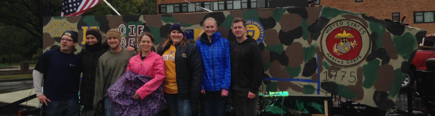 Students of the Veterans Club stand in front of the homecoming float
