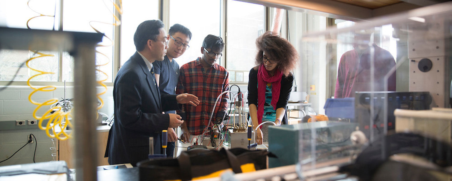 Students gather near a professor during lab sessions.